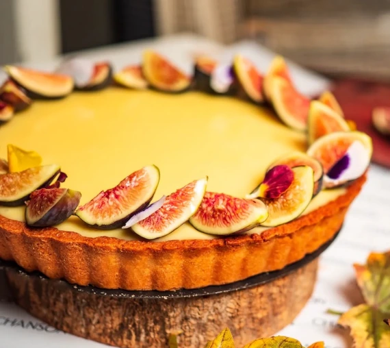 Elegant lemon tart decorated with fresh figs and edible flowers.